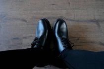 Pés masculinos em casual limpo par de botas pretas no chão de madeira — Fotografia de Stock