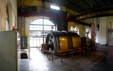Промышленная круговая машина с металлическим механизмом, расположенная внутри заброшенного бесхозного ветхого промышленного цеха с легкими стенами и большими арочными окнами — стоковое фото