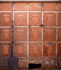 Shabby old high wall of abandoned red brick building with brick windows ruined entrance and pipes with dirty black smudges — Stock Photo