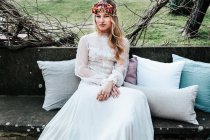Young bride sitting on bench in garden — Stock Photo