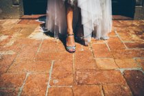 Crop bride in white wedding dress dancing near entrance of old building — Stock Photo
