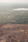 Von oben eine reisende Frau in Freizeitkleidung, die im Sommerurlaub in Sigiriya vor dem Hintergrund des Tals mit Wald und See bergauf läuft — Stockfoto