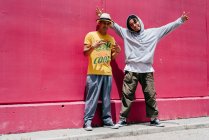 Deux jeunes danseurs urbains debout près d'un mur rose dans la rue — Photo de stock