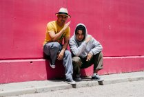 Two young urban dancers standing near to a pink wall on the street — Stock Photo