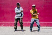 Two young men dancing near to a pink wall on the street — Stock Photo