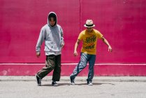 Deux jeunes hommes dansant près d'un mur rose dans la rue — Photo de stock