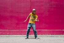 Молодые латиноамериканцы танцуют рядом с розовой стеной на улице — стоковое фото