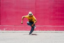 Junge hispanische Männer tanzen in der Nähe einer rosa Wand auf der Straße — Stockfoto