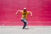 Молоді іспаномовні чоловіки танцюють біля рожевої стіни на вулиці — стокове фото