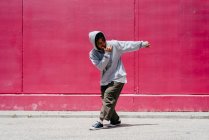Jóvenes hispanos bailando cerca de una pared rosa en la calle - foto de stock