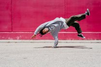 Jovens hispânicos fazendo acrobacias perto de uma parede rosa na rua — Fotografia de Stock