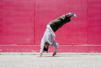 Junge hispanische Männer machen Akrobatik in der Nähe einer rosa Wand auf der Straße — Stockfoto