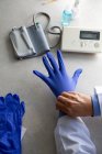Чоловік лікар одягає хірургічні рукавички, обрізаний постріл — стокове фото