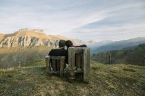 Paar sitzt auf Holzbänken auf einem abgelegenen grünen Hügel und genießt die Aussicht während eines Spanienbesuchs — Stockfoto