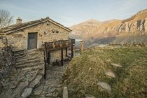 Vecchia casa in pietra con tetto piastrellato e con terrazza in legno situata in un terreno roccioso in Cantabria — Foto stock