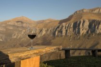 Copa de vino tinto con montañas y cielo azul sobre fondo, Cantabria - foto de stock