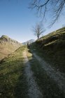Caminhantes caminhando pela estrada rural na encosta da colina verde em montanhas rochosas durante a viagem à Espanha — Fotografia de Stock