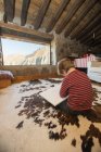 Junge sitzt auf dem Boden auf gemütlichen Teppich und zeichnet mit Buntstiften in Skizzenbuch kühlen gemütlichen Wohnzimmer des Steinhauses in Kantabrien — Stockfoto