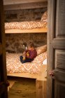 Концентрированный ребенок в повседневной одежде сидит на удобной кровати в спальне и играет на укулеле во время охлаждения дома в Кантабрии — стоковое фото