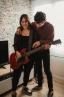 Mann lehrt Frau zu Hause Gitarre spielen — Stockfoto