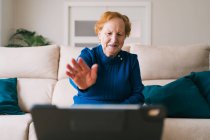 Mujer mayor comunicarse con un amigo durante el chat de vídeo en el ordenador portátil - foto de stock