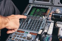 Crop anonymous male pilot using keyboard of flight management system in cockpit of modern aircraft during flight — Stock Photo