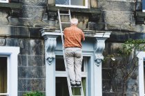 Homem anônimo sênior reparando a porta da antiga mansão — Fotografia de Stock