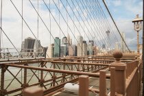 Grattacieli contemporanei di New York visti attraverso i cavi del ponte di Brooklyn contro il cielo blu nuvoloso — Foto stock