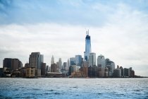 Современные небоскребы Нью-Йорка видны с реки на фоне голубого облачного неба в солнечный день — стоковое фото