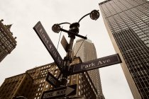 Снизу односторонние дорожные знаки на перекрестке с современными высотными зданиями на фоне Нью-Йорка — стоковое фото