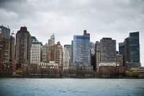 Contemporary skyscrapers of New York City seen from river against blue cloudy sky in sunny day — Stock Photo
