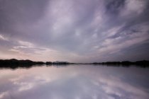 Туманное небо, отражающееся в спокойной озерной воде — стоковое фото
