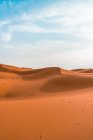 Minimalistische Wüstenlandschaft mit Sanddünen unter blauem bewölkten Himmel — Stockfoto