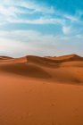 Paisagem minimalista do deserto com dunas arenosas sob céu azul nublado — Fotografia de Stock