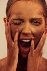 Attraktives weibliches Modell mit Schokolade auf der Haut, das Gesicht berührt und mit geschlossenen Augen in die Kamera brüllt — Stockfoto