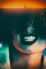 Обрізати жіночу модель в синтетичній перуці і з чорною помадою, що показує зуби під барвистим світлом — стокове фото