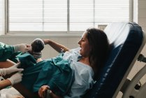 Strained female grasping handle and grunting in pain while giving birth to baby on medical chair in modern hospital — Stock Photo