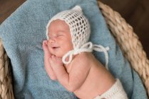 Top view of newborn baby wrapped in cloth lying on soft blanket and sleeping in wicker basket on floor at home — Stock Photo