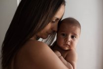 Erwachsene Frau umarmt und berührt niedlichen Säugling sanft, während sie zu Hause zusammen ruht — Stockfoto