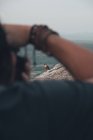 Visão traseira da cultura sem rosto turista masculino em pé na montanha rochosa e tirar fotos de águia montesa sentado na borda do penhasco na noite de verão — Fotografia de Stock