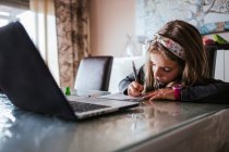 Mädchen erledigt Hausaufgaben vom Laptop aus — Stockfoto