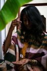 Молода етнічна жінка-шаманка в традиційному вбранні тримає підвісний кристал і виконує таємничий ритуал — стокове фото