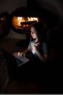 From above of content female sitting on floor and warming with cup of hot beverage while using netbook and chilling during weekend at home — Stock Photo