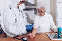 Опекун делает инъекции для пожилого пациента дома — стоковое фото