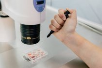 Von oben beschnitten unkenntlich Arzt Hand injizierte Eizelle auf Petrischale und Untersuchung der Zelle durch Mikroskop im Labor der modernen Fruchtbarkeitsklinik — Stockfoto