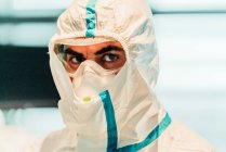 Porträt eines seriösen Berufsarztes in Schutzuniform und Maske, der im modernen Operationssaal steht und in die Kamera blickt — Stockfoto