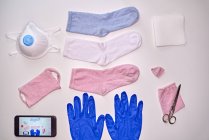 Vue du dessus des chaussettes gants serviette smartphone et ciseaux pour fabriquer un masque en tissu pendant la période de quarantaine du coronavirus pour la protection — Photo de stock