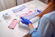 Anonyme Person in blauen sterilen Handschuhen, die zeigt, wie man während der Quarantäne des Coronavirus zu Hause eine Gesichtsmaske mit Socken herstellt — Stockfoto