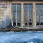 Esterno di edificio industriale in pietra abbandonato con strette finestre con griglia metallica e vetri rotti — Foto stock