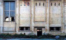 Экстерьер заброшенного каменного промышленного здания с узкими окнами с металлической сеткой и разбитого стекла — стоковое фото